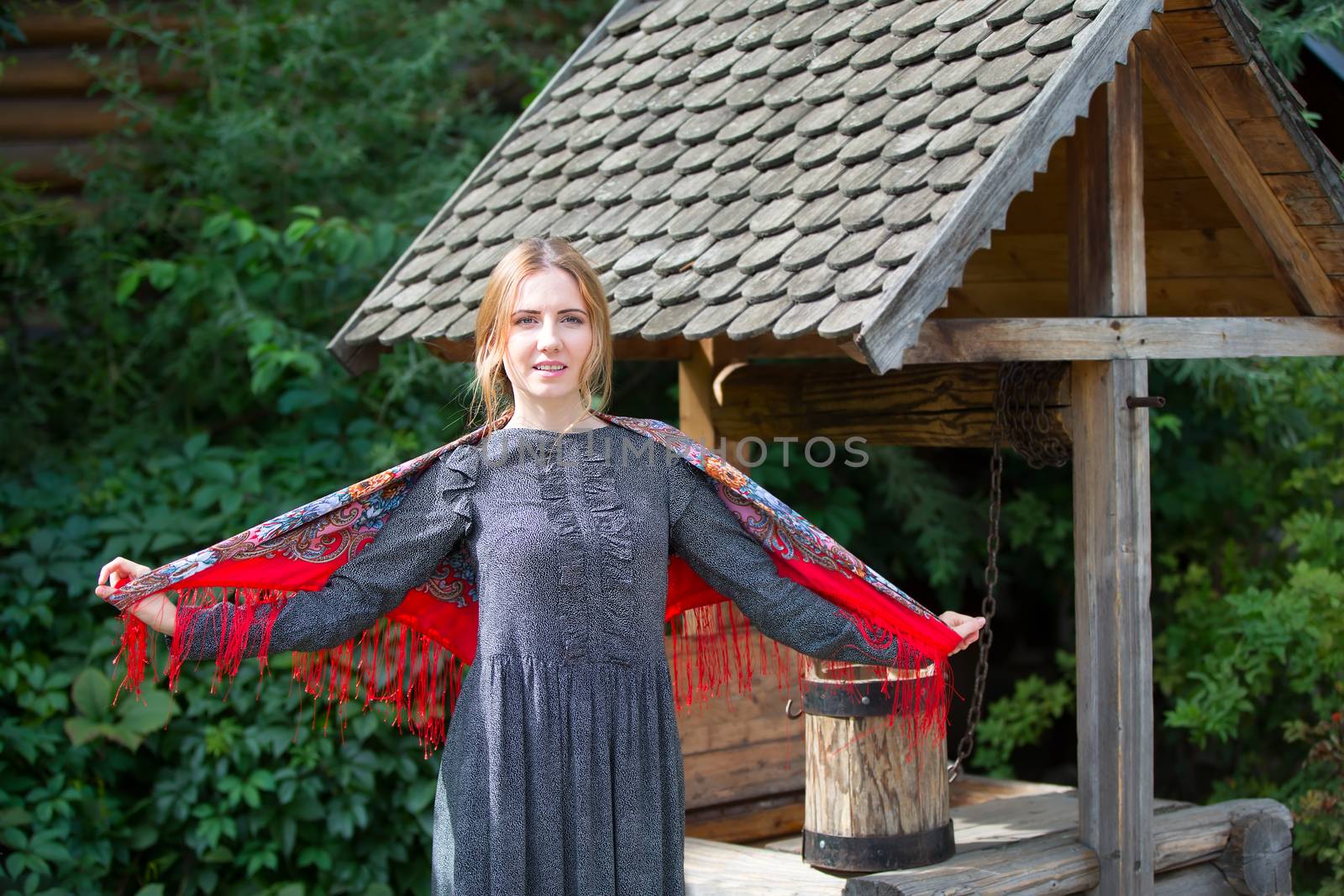 Russia, Moscow, Izmaylovsky Park, August 27, 2017. International Photo Festival.A Russian woman in a scarf with a bucket at the well. Russian woman. A woman with a Russian handkerchief.