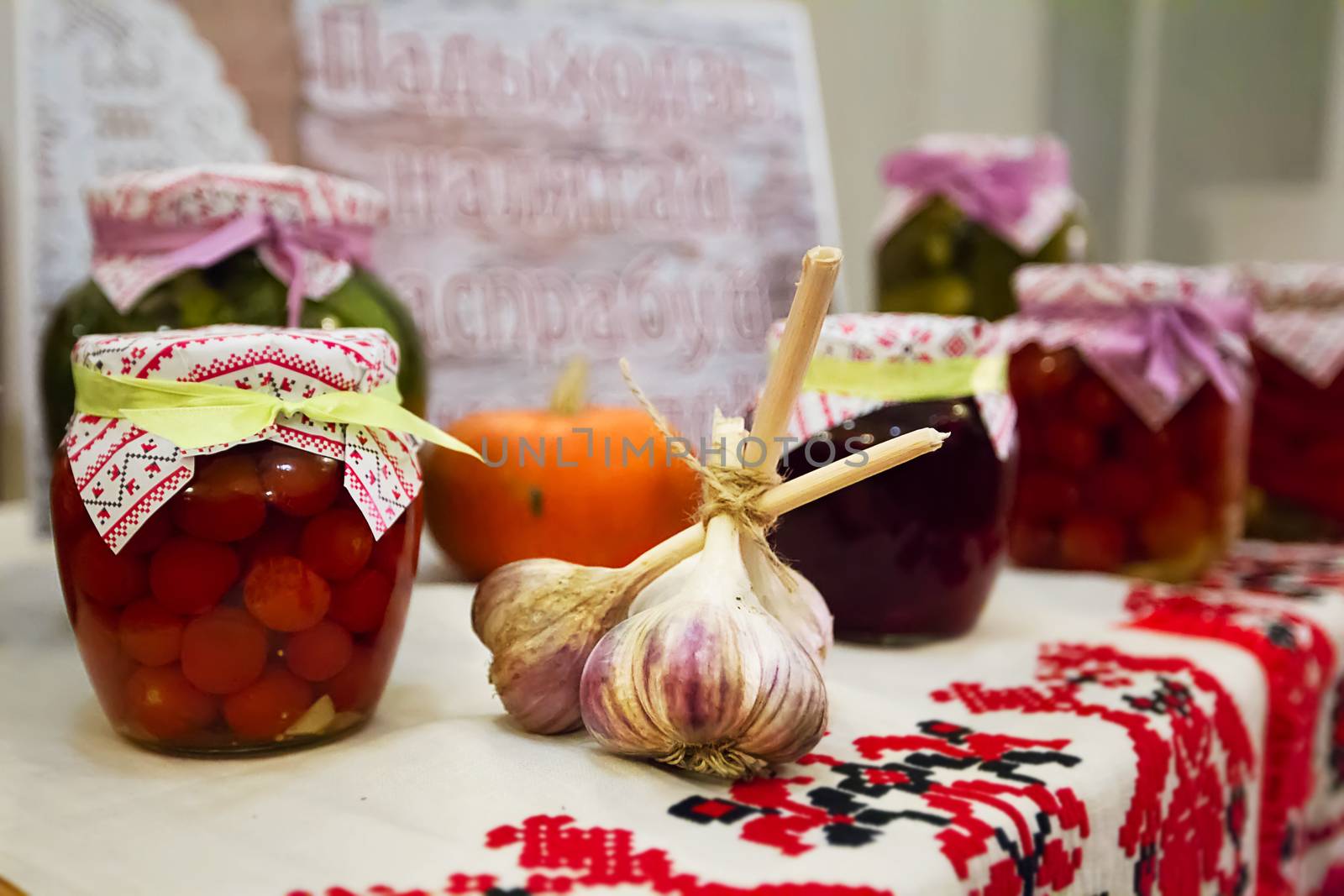 Preservation of vegetables. Canned tomatoes. Head of garlic. Belarusian products on the Belarusian towel. National Belarusian cuisine
