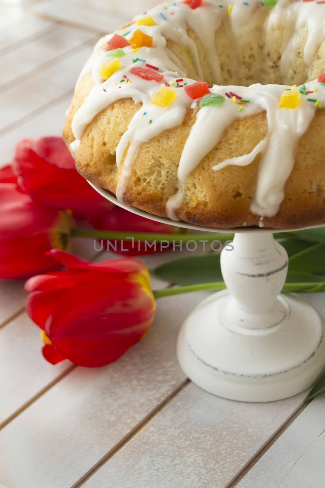 Easter babka cake and bright tulips on a vintage table. Easter family breakfast. Vertical image