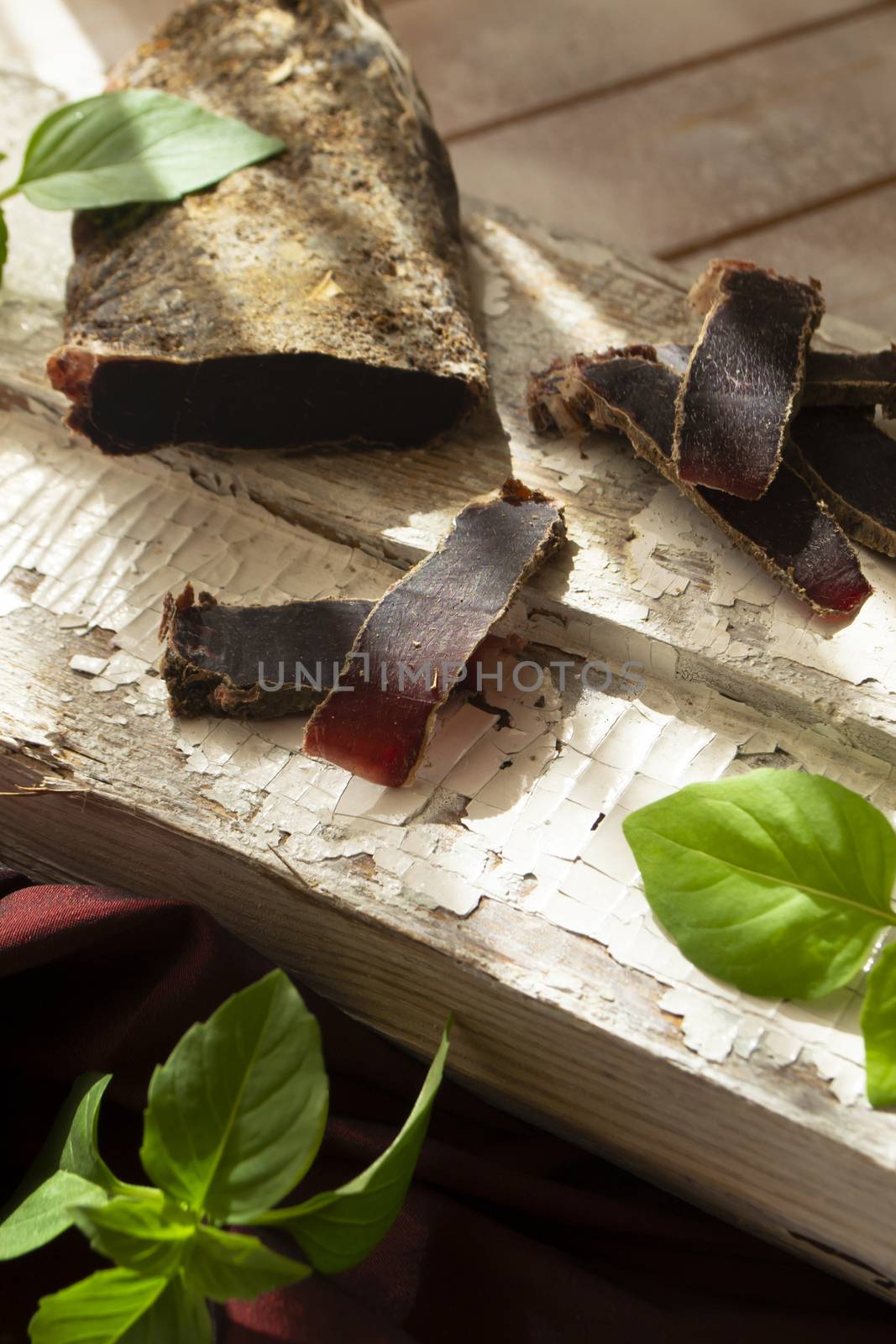 jerked meat, wild deer dry meat on a rustic table, vertical image