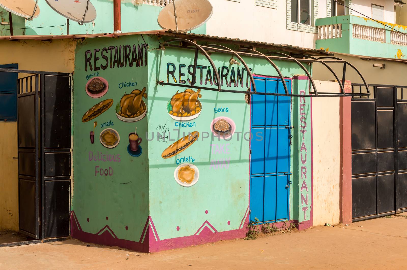 BIJILO, GAMBIA-January 06, 2020: Mural on a facade representing the dishes sold in a restaurant on a road from Bijilo in The Gambia, West Africa