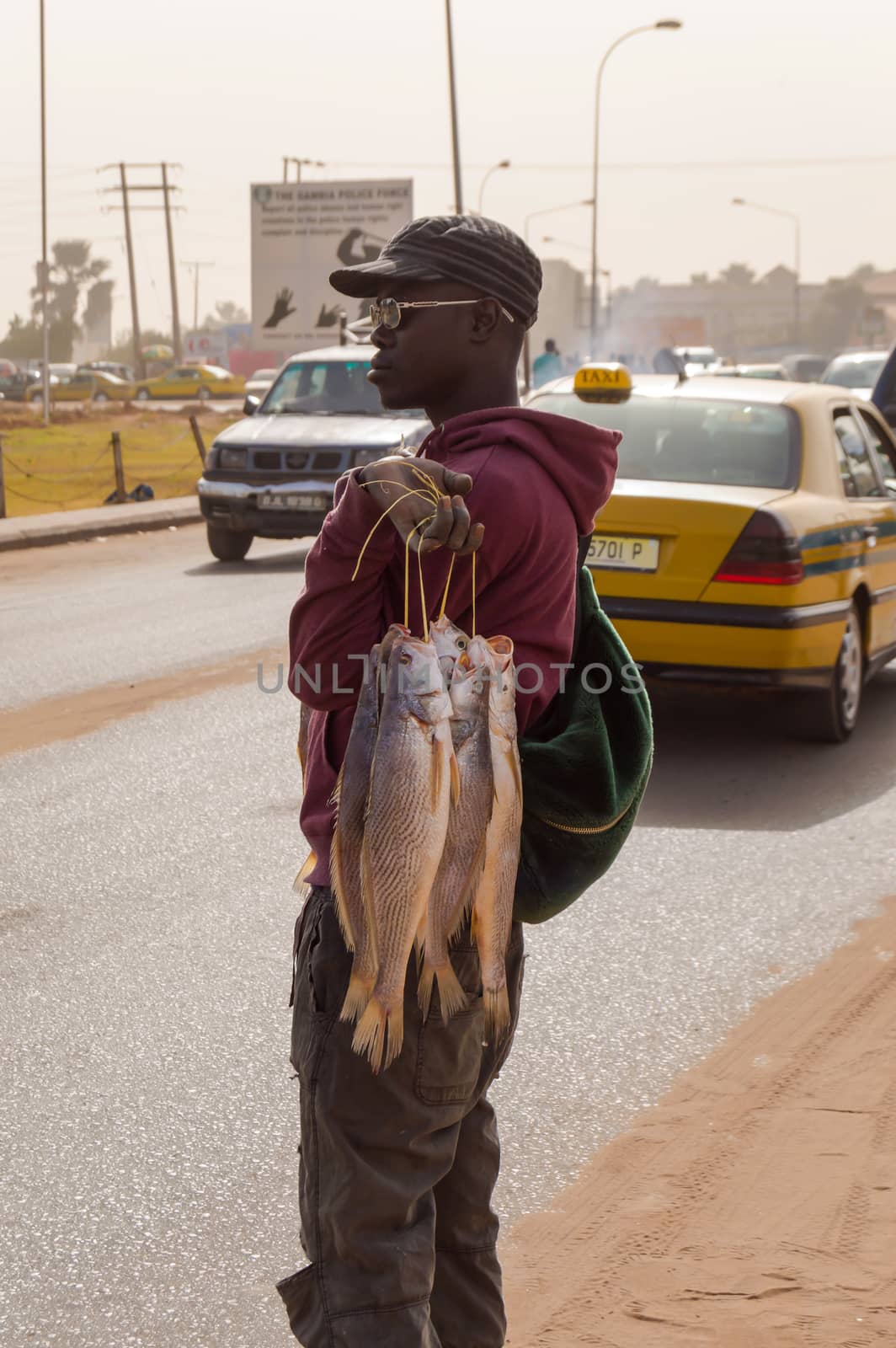Bijilo, Gambia, January 2020; Young seller of fresh fish on the street on a road from Bijilo in The Gambia, West Africa