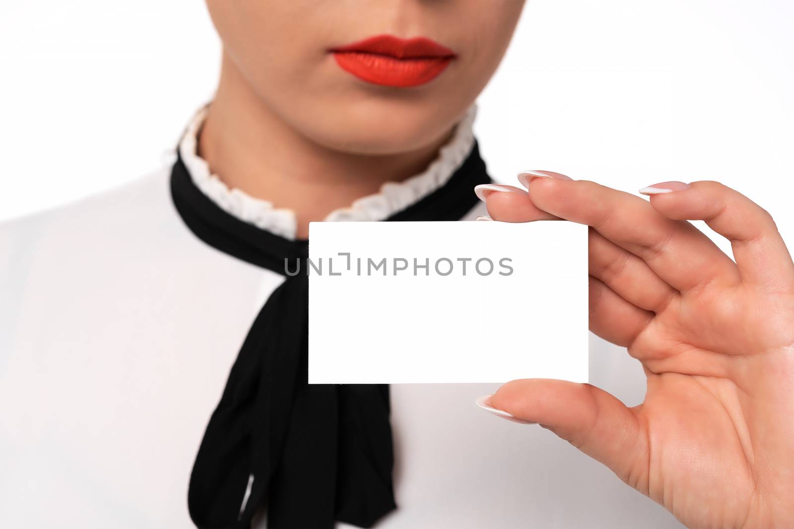 Young business woman with perfect fingernails holds blank business card in close-up.