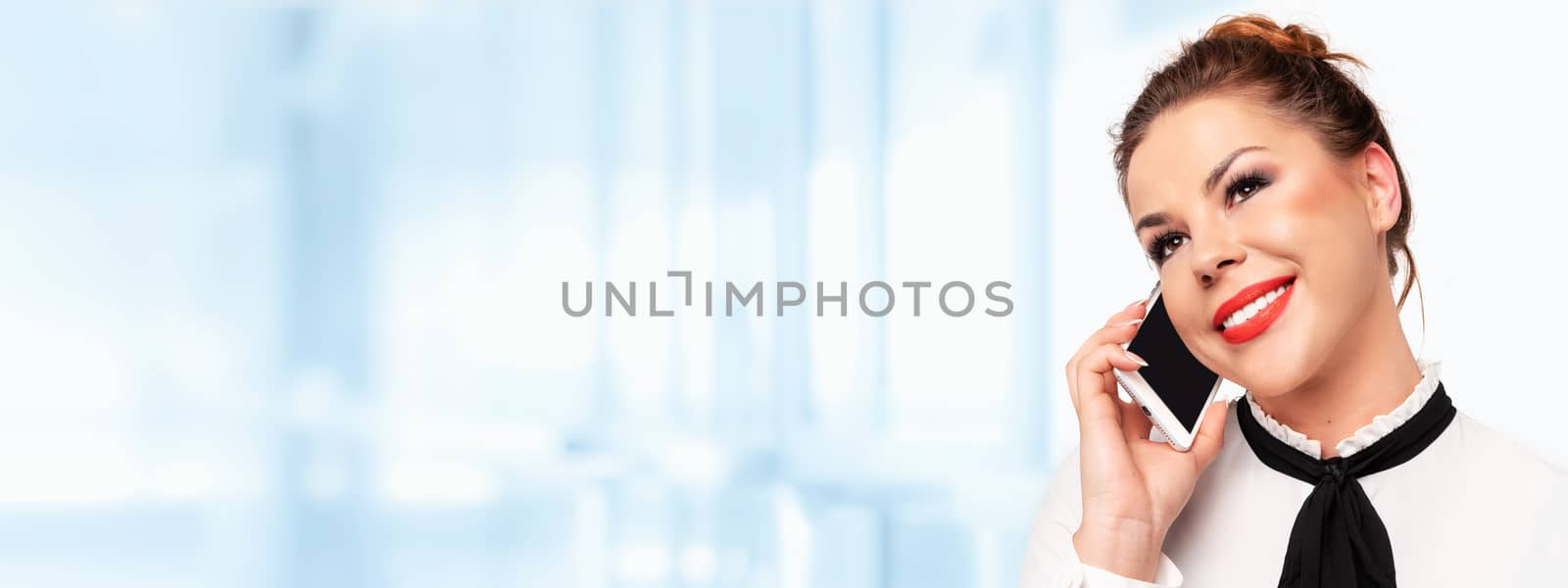 Modern communications banner -  beautiful young business woman talking on a mobile phone and smiling (copy space).