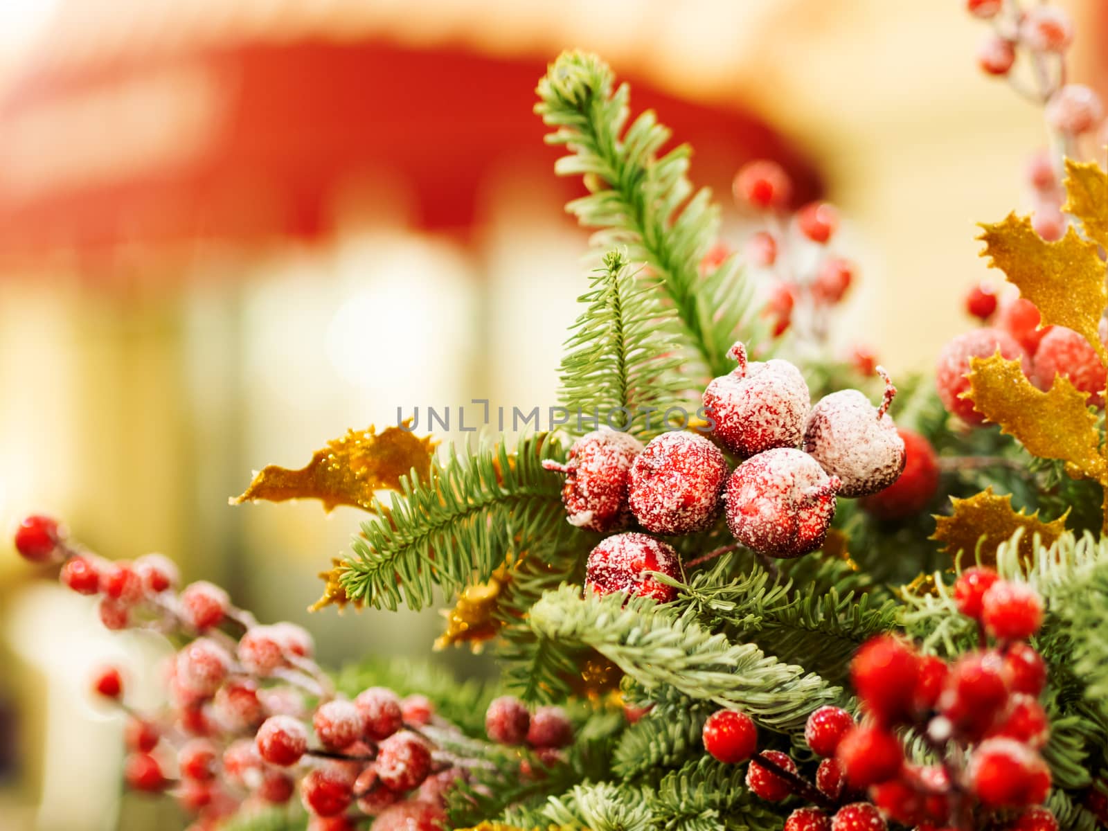 Christmas and New Year background with fir tree wreath and berries. Shiny golden decorations and light bulb bokeh.