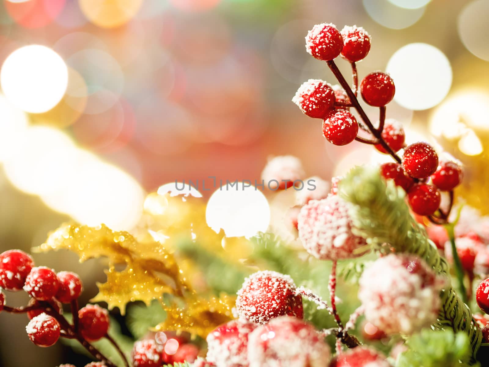 Christmas and New Year background with fir tree wreath and berries. Shiny golden decorations and light bulb bokeh.