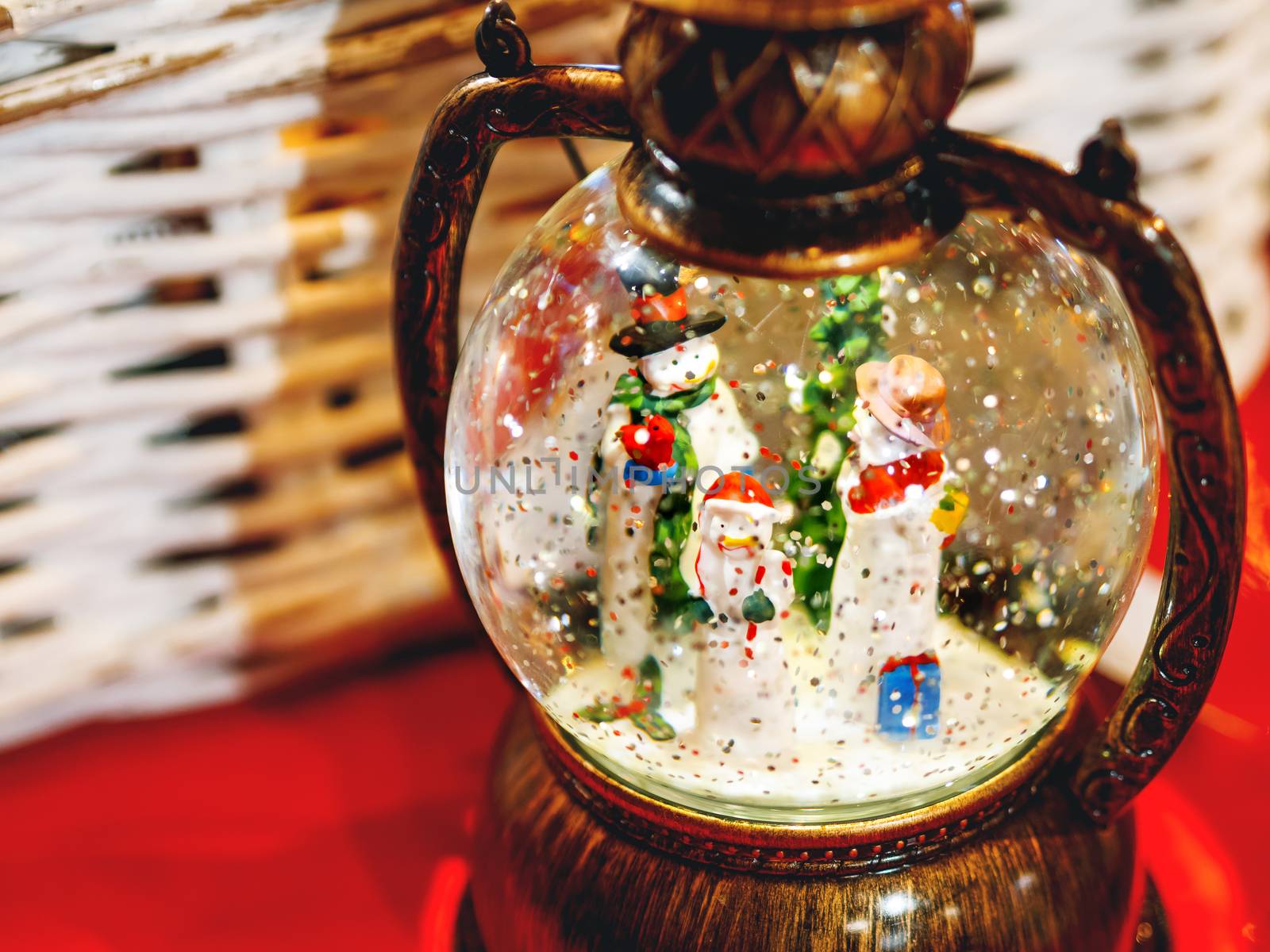 Three snowmen inside vintage snow globe with spangles. Christmas retro toy.