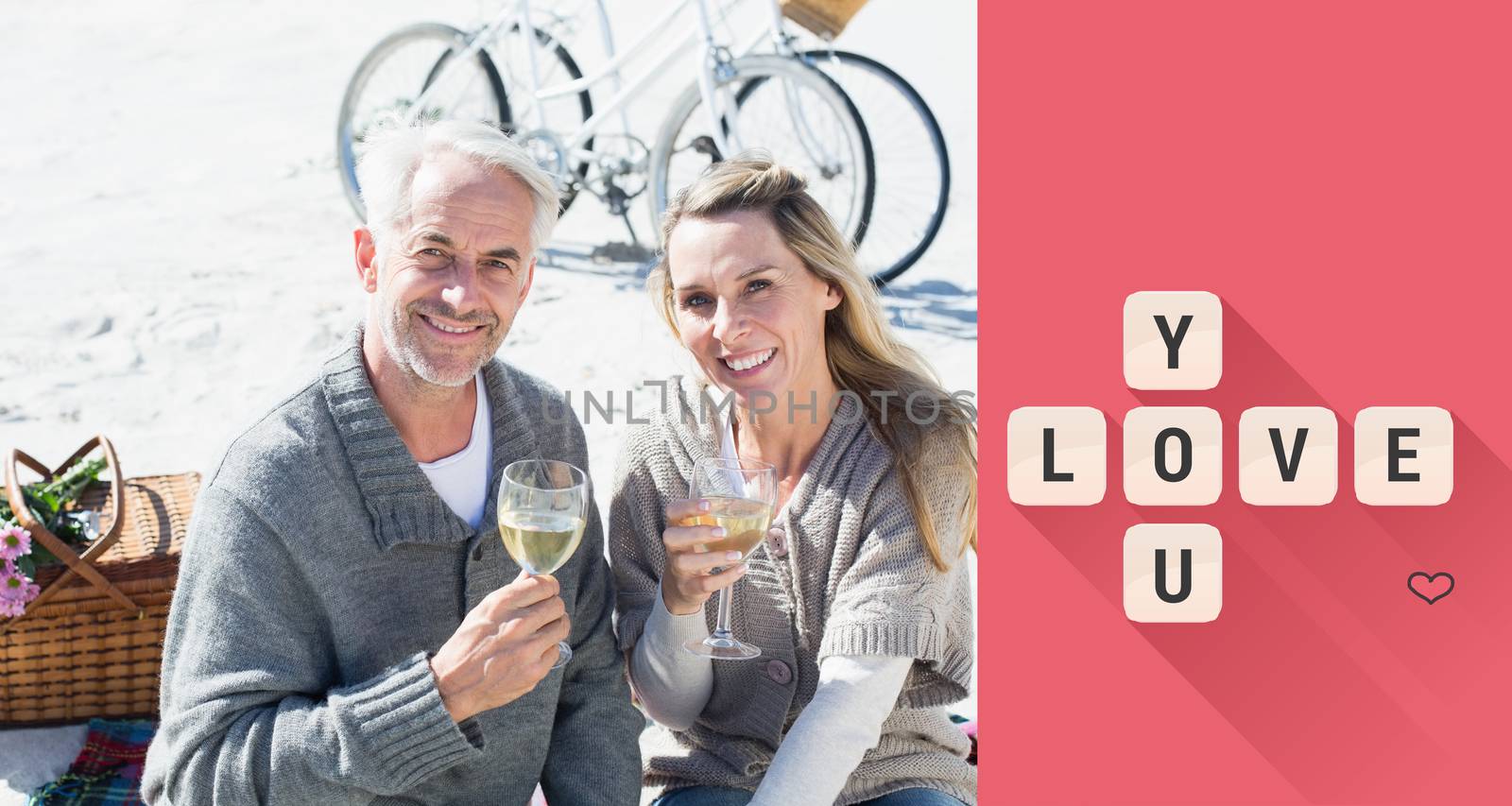 Couple enjoying white wine on picnic at the beach smiling at camera against love you tiles