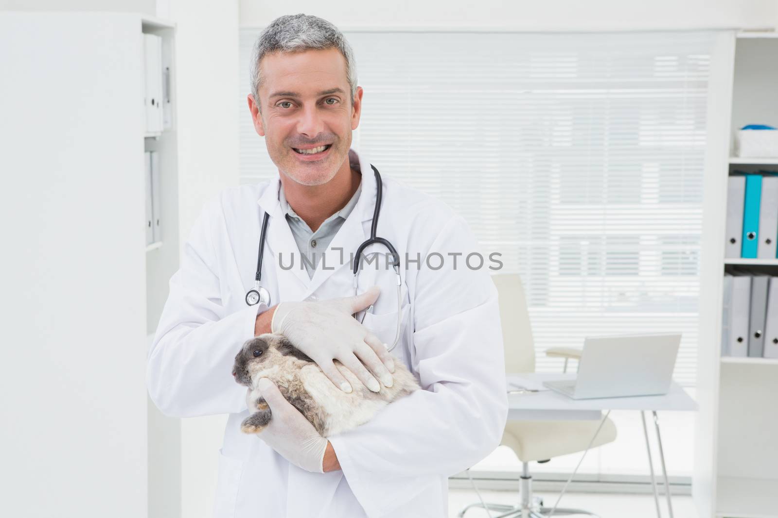 Smiling vet with a rabbit in his arms by Wavebreakmedia