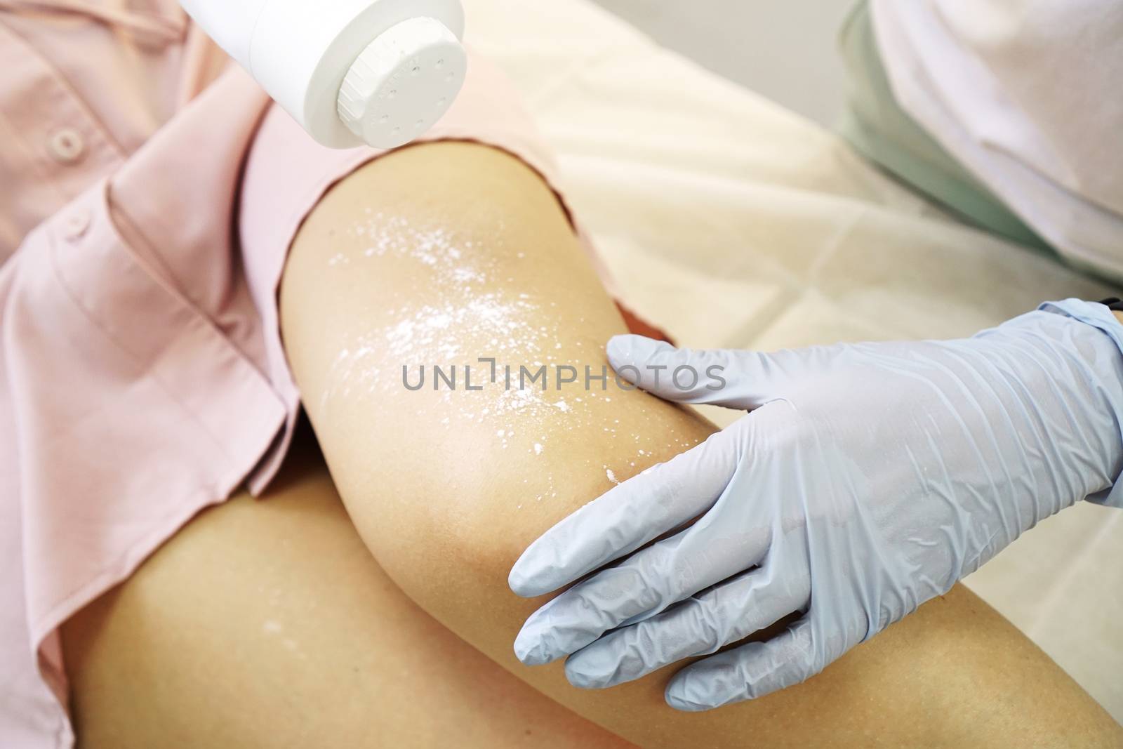 Woman using powder talc for sugaring process. Hair removal from beautiful female legs. Waxing in a beauty salon. Close-up of doctor hands in gloves