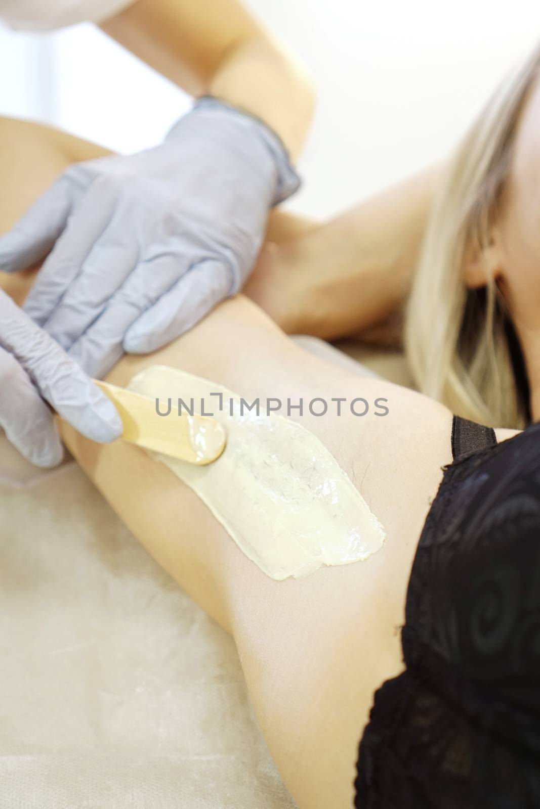 Waxing woman armpit with spatula. Salon wax beautician epilation procedure by natali_brill