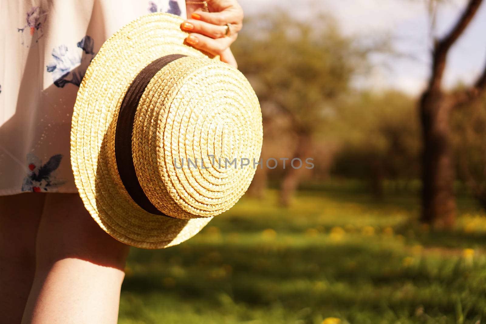 Close-up photo - girl in a straw hat holding a hat in her hands in summer garden