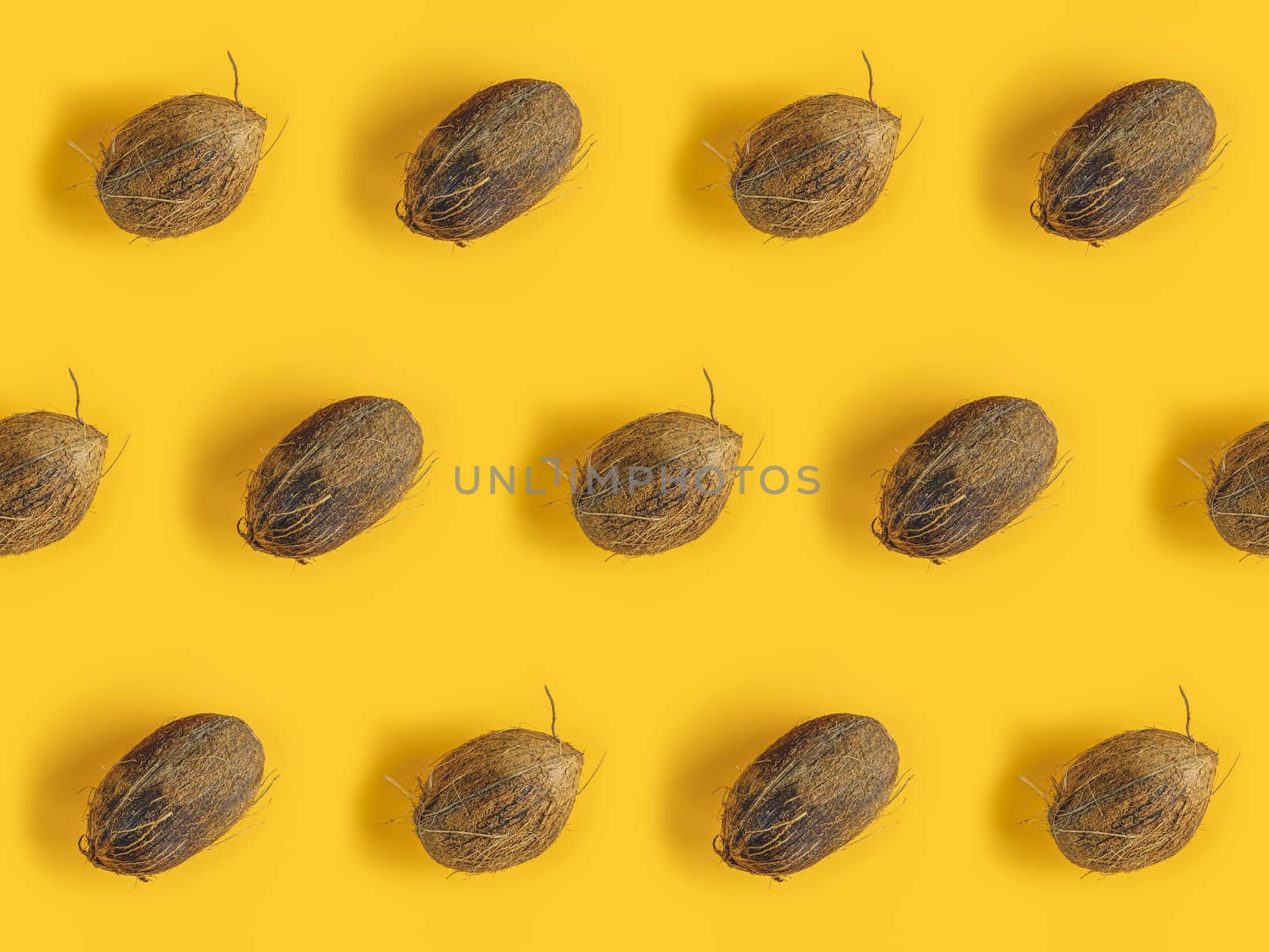 Pattern with ripe coconuts on yellow background. Top View. Copy Space. Pop art design, creative summer concept. Coconut in minimal flat lay style