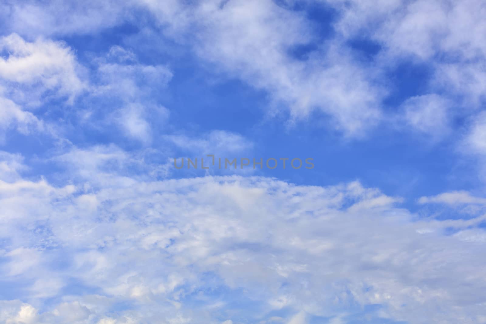 Blue sky background with the texture of white and fluffy, fun clouds.