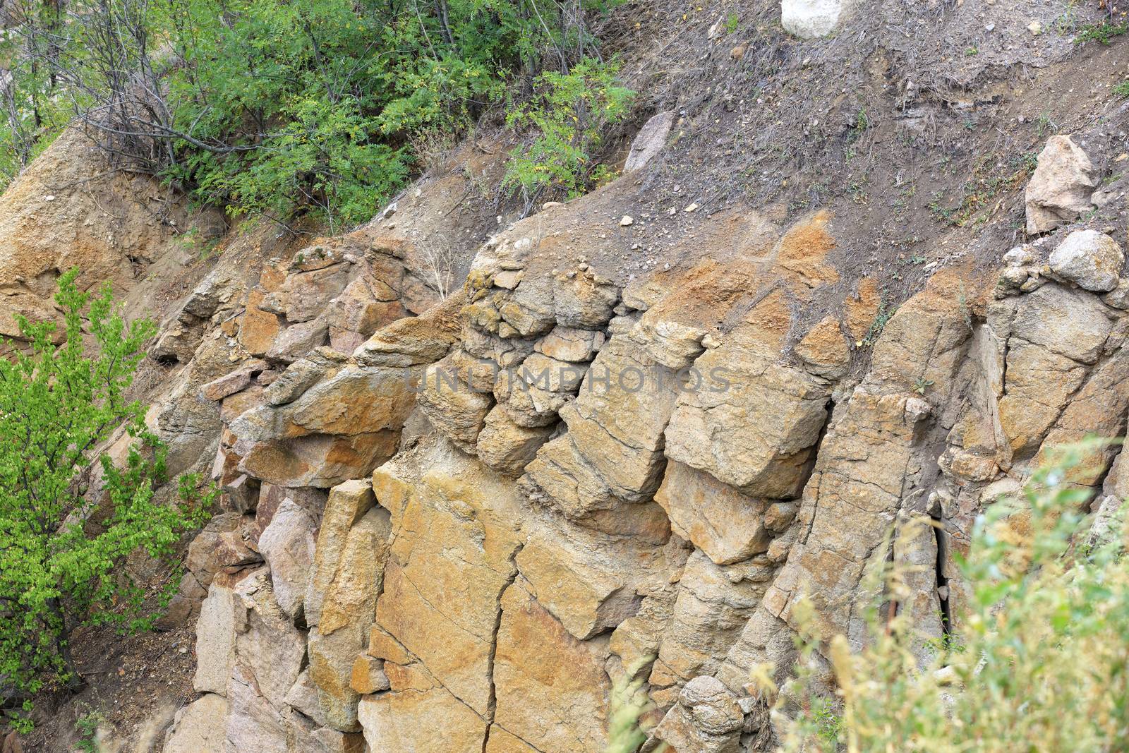 Erosion, destruction of soil and rock on a hillside after heavy rain among green vegetation.