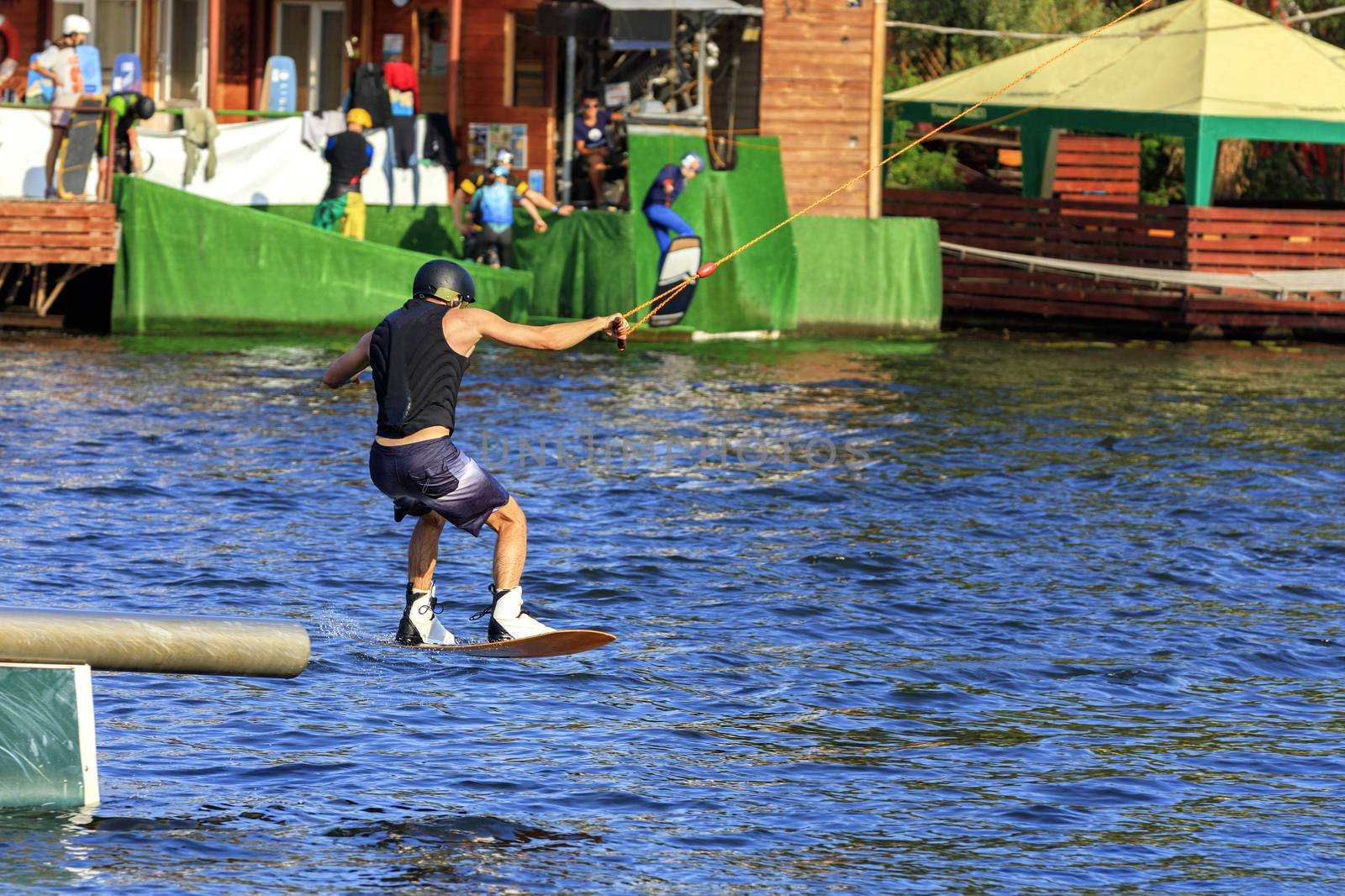 A wakeboarder rushes through the water at high speed overcoming various obstacles and performing tricks.