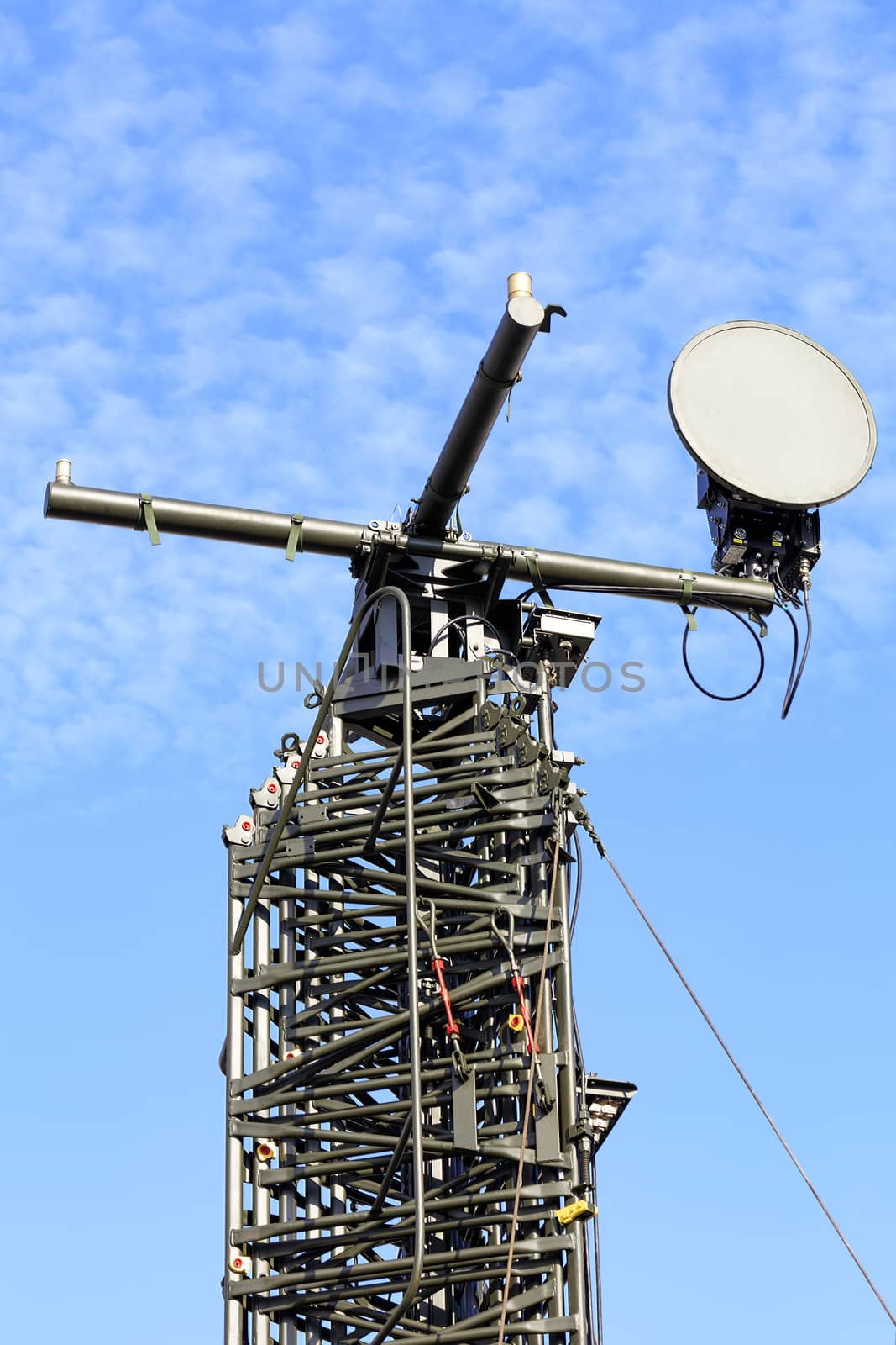 Retractable telecommunications mast with a field TV antenna for the implementation of radio interception of enemy enemy signals in wartime against a peaceful blue sky.