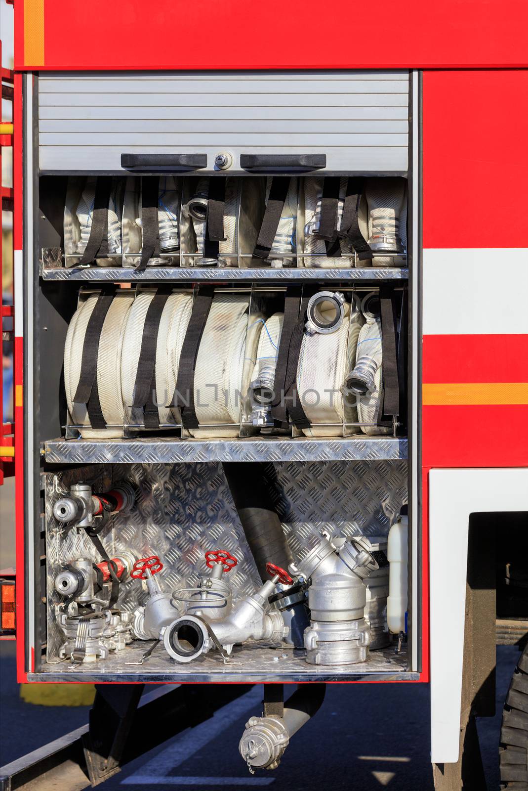 Fire hoses, valves and cranes are located in the cargo compartment of an equipped fire truck. by Sergii