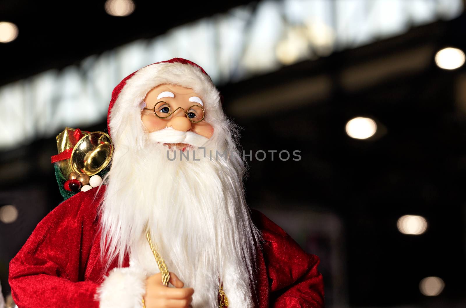 Decorative toy Santa Claus in a red fur coat against the background of the night city. by Sergii