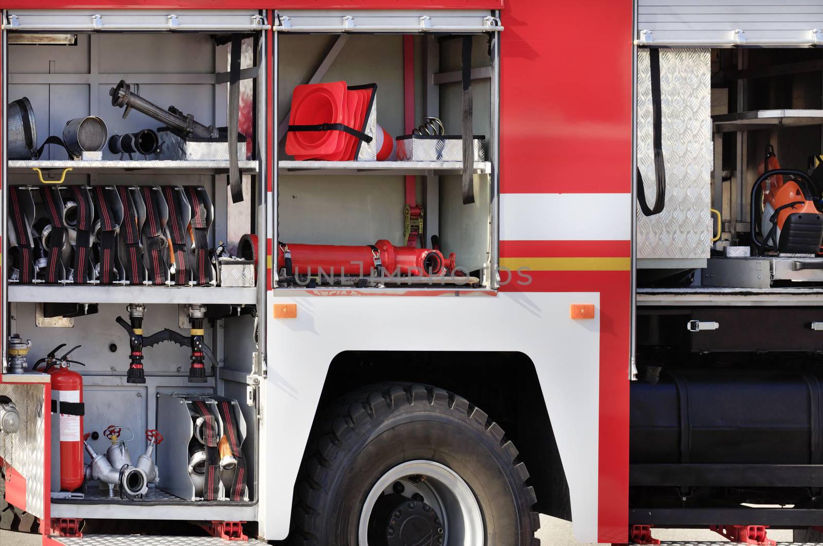 Fire hoses, valves and cranes, transport cones, manual fire extinguishers are located in the cargo compartment of an equipped fire truck. by Sergii