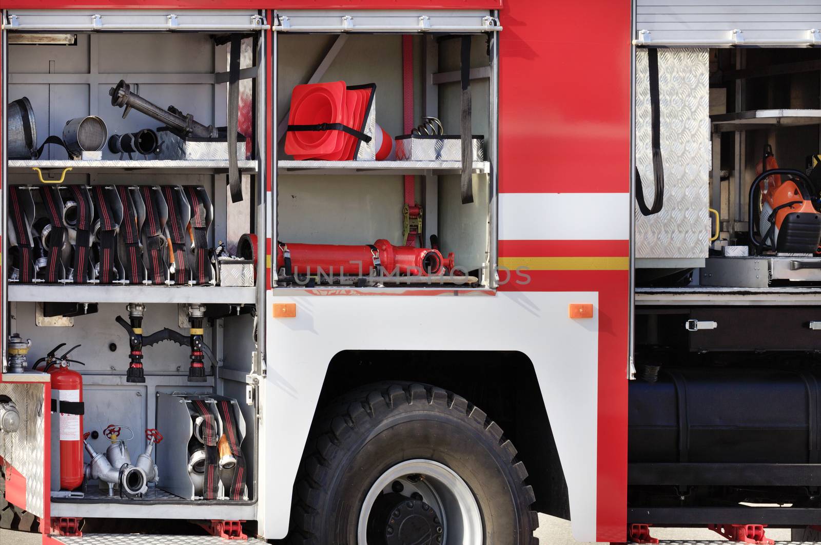 Fire hoses, valves, cranes, road cones, hydrants and manual fire extinguishers are located in the cargo compartment of an equipped fire truck, free copy space.