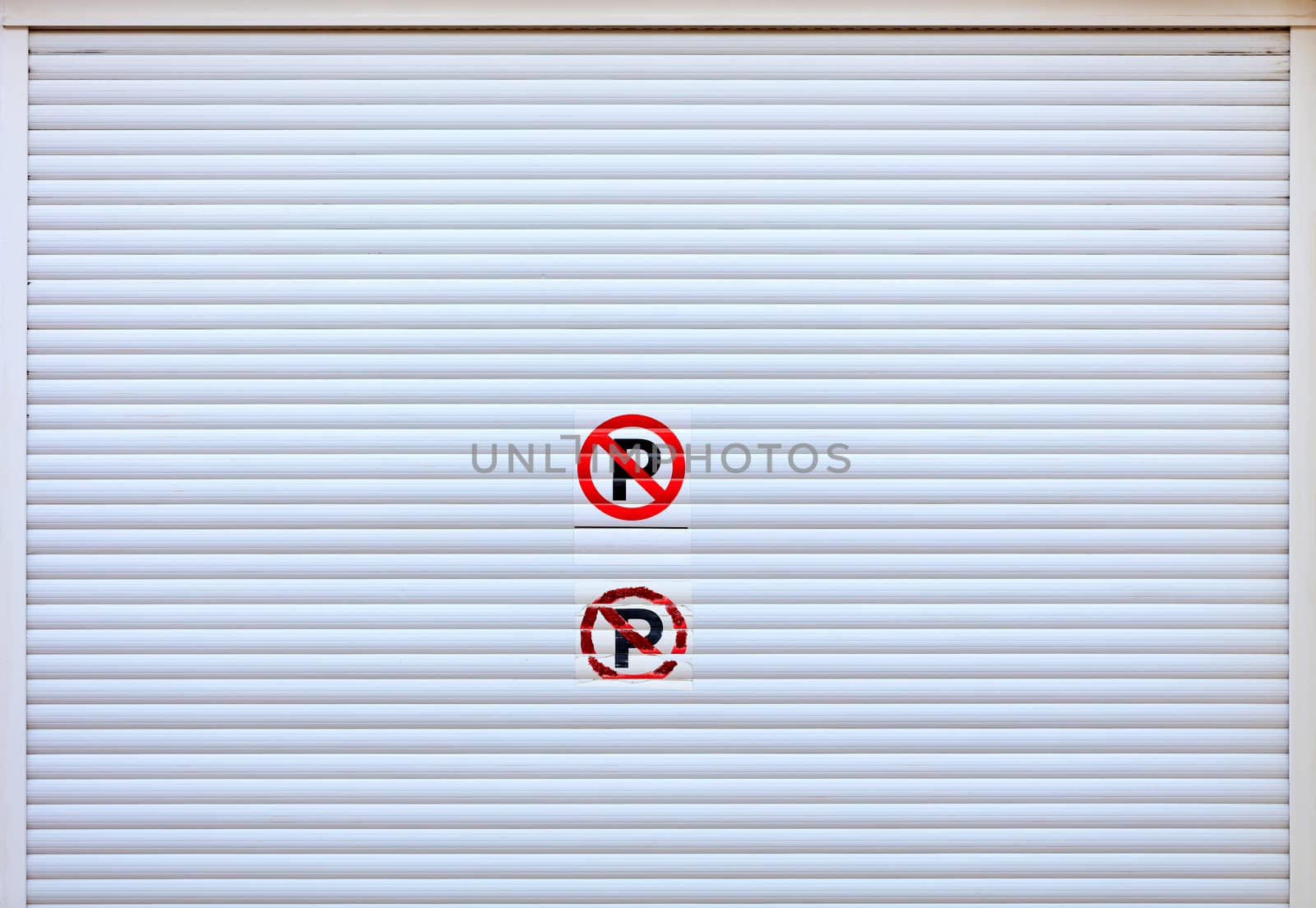 Large white metal shutters at the entrance to the car parking. by Sergii