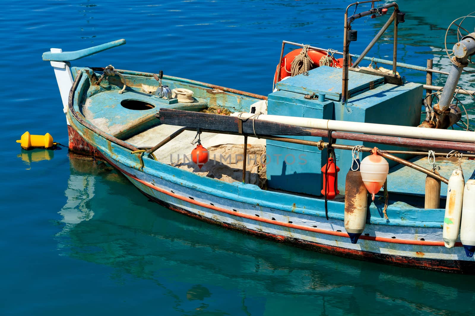 An old fishing boat anchored in the clear waters of the Ionian Sea. by Sergii