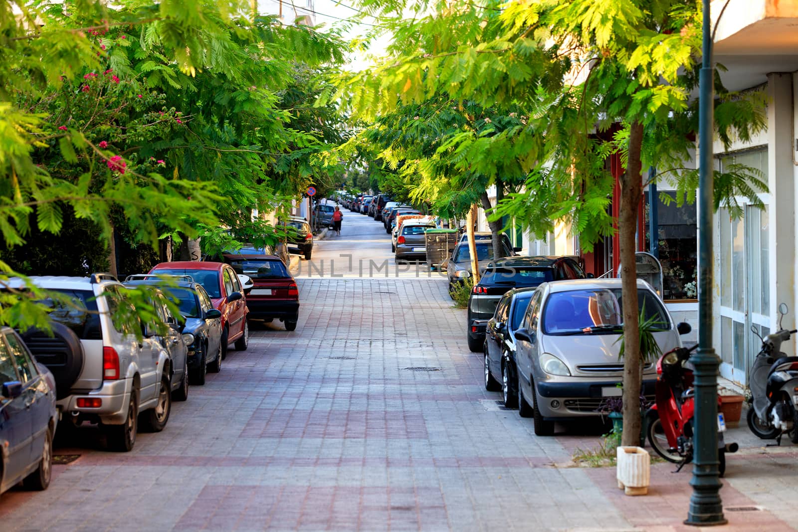 The pedestrian part of the road is blocked by parked cars along the road on a narrow city street in the early morning. by Sergii