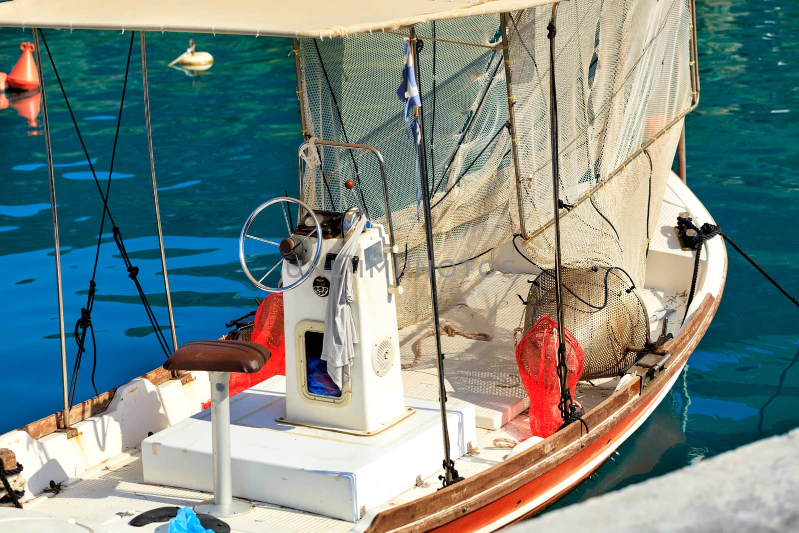 View of the captain's bridge and steering wheel of a small wooden fishing schooner with hanging fishing tackle. by Sergii