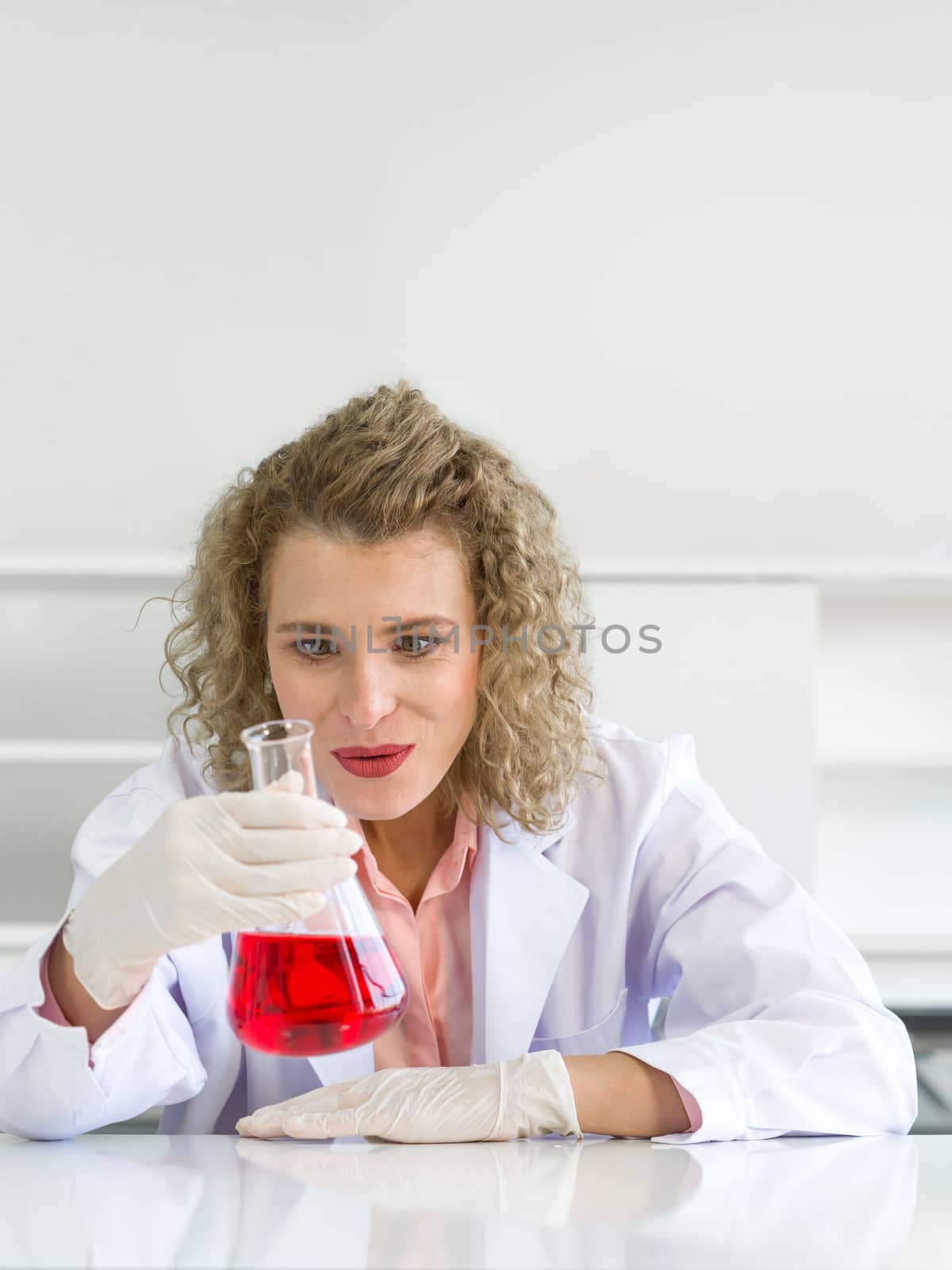 The young blonde scientist showed a happy face with the results of the chemistry experiment. Working atmosphere in chemical laboratory.