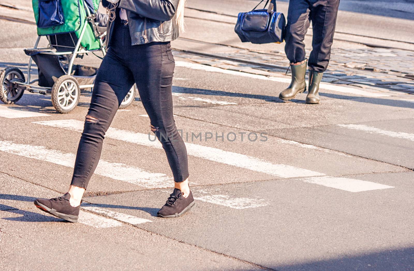 young woman feet, crossing an urban street on sunny spring day
 