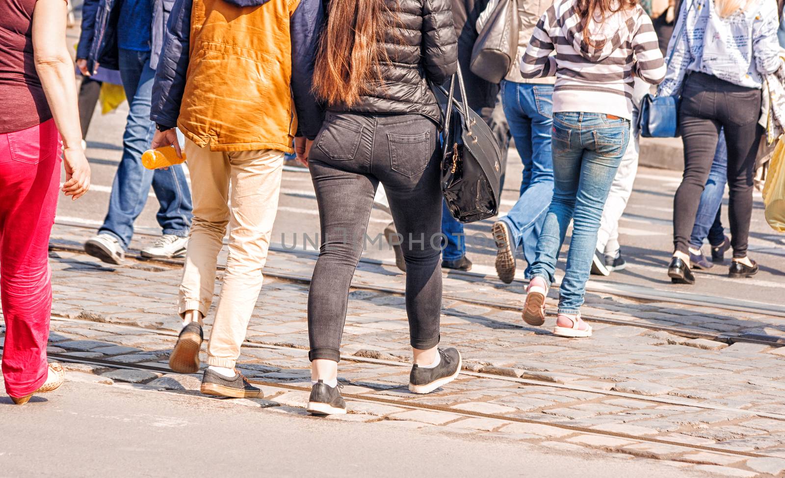 young women feet, crossing an urban street on sunny spring day