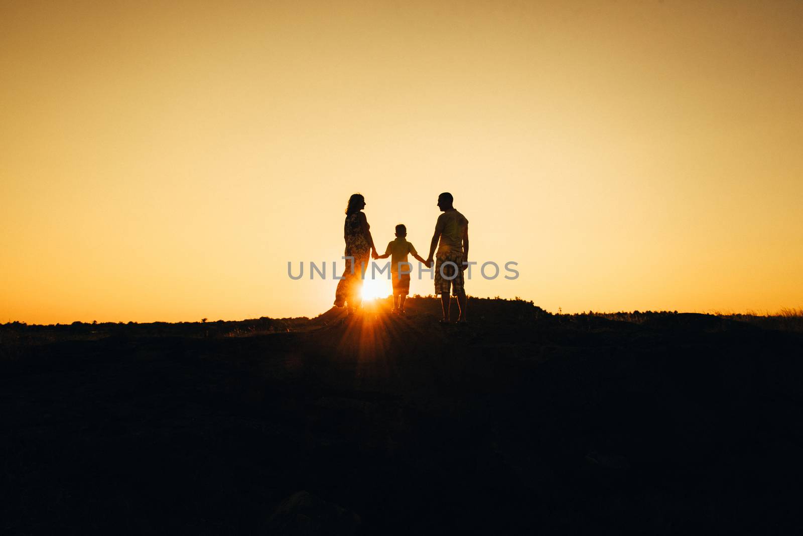 silhouettes of a happy young happy family against an orange sunset in the desert