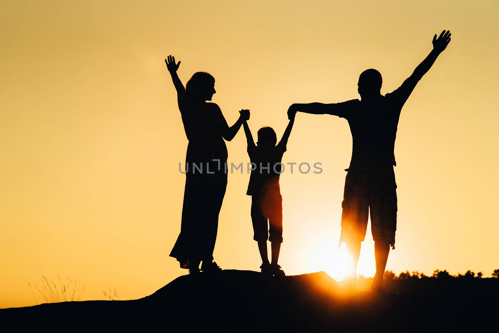 silhouettes of a happy young happy family against an orange suns by Andreua