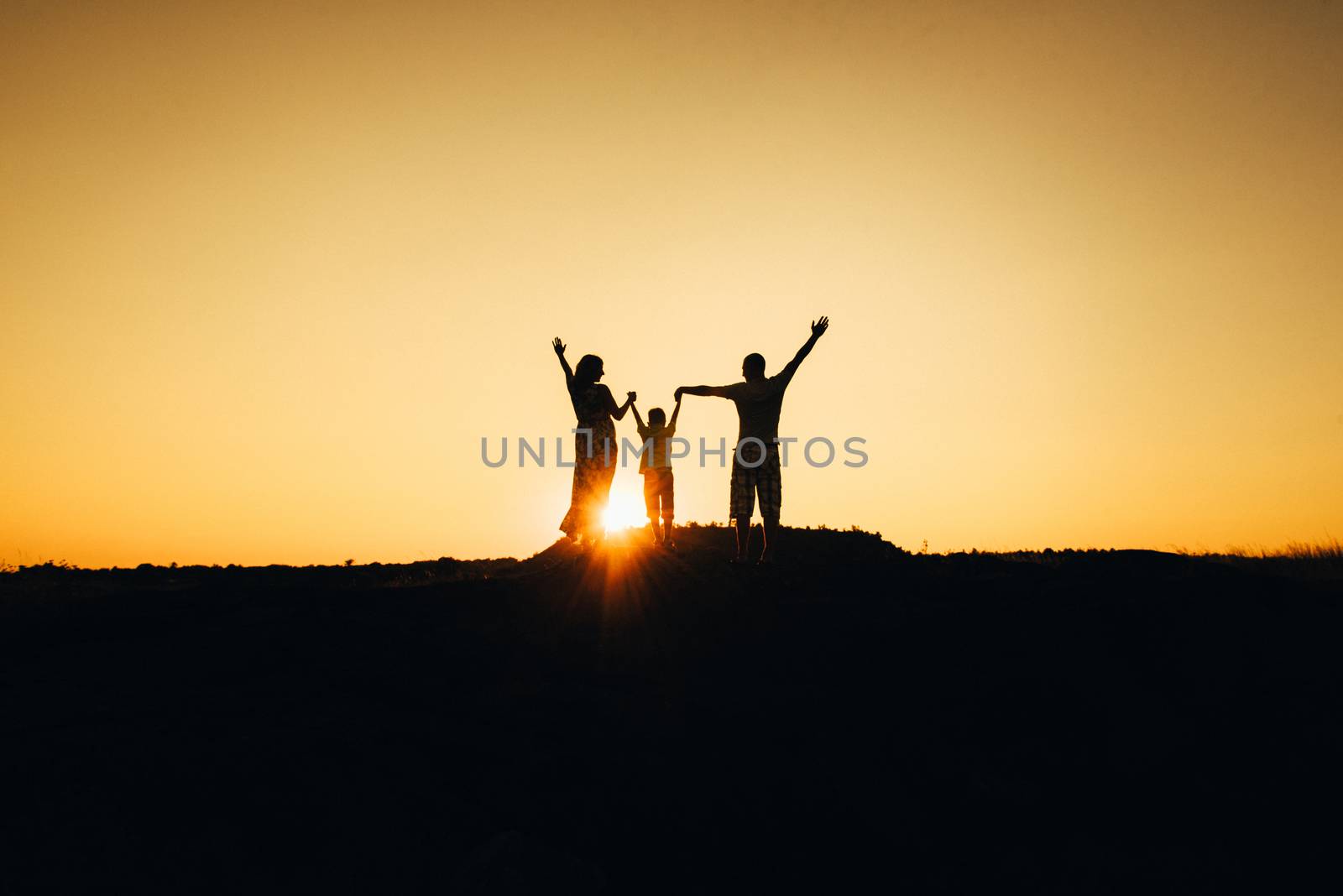 silhouettes of a happy young happy family against an orange sunset in the desert