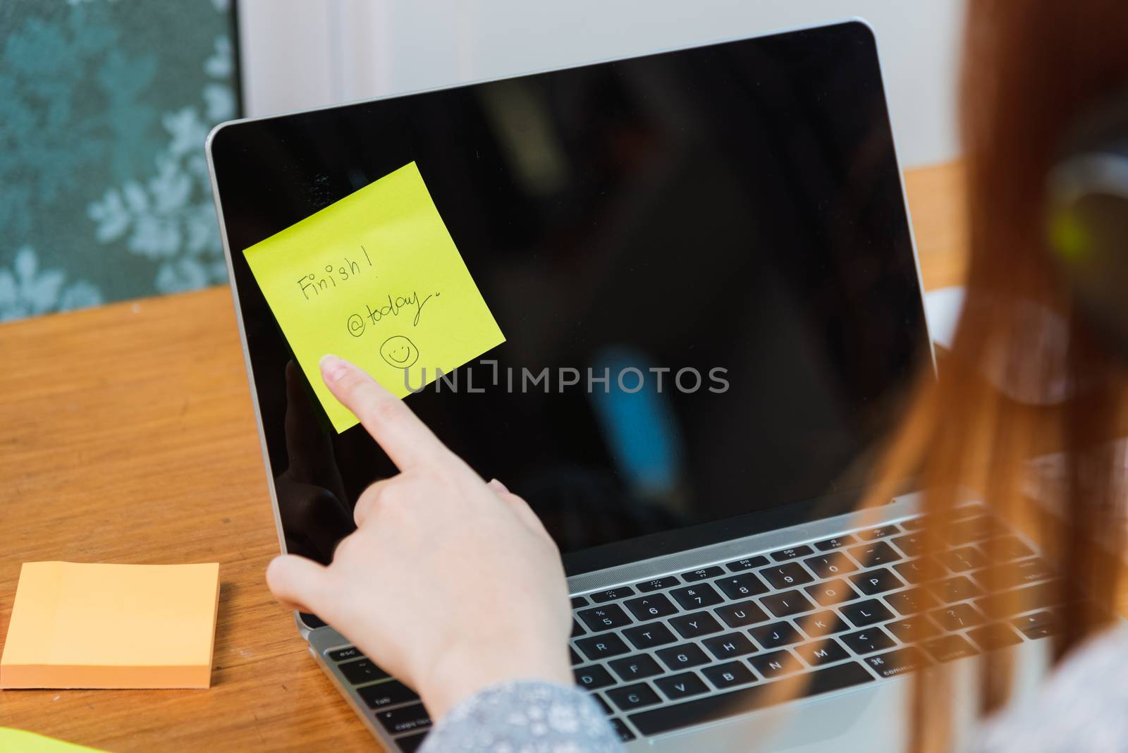 Work from home concept, Hands of Asian young woman, student girl point small piece yellow paper write "finish today" stick on screen laptop computer at home office
