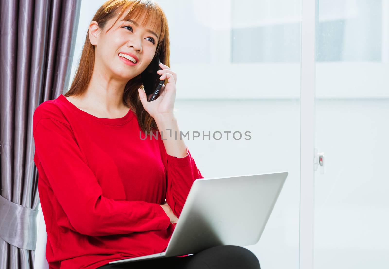Work from home concept, Asian beautiful young woman smiling, student girl sitting on chair using mobile phone call director to team during working with laptop computer at home office
