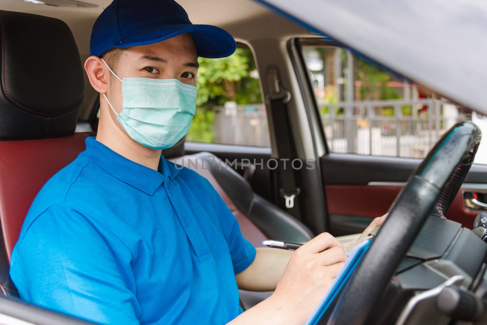 Asian delivery courier young man driver inside the van car with parcel post boxes checking amount he protective face mask, under curfew quarantine pandemic coronavirus COVID-19