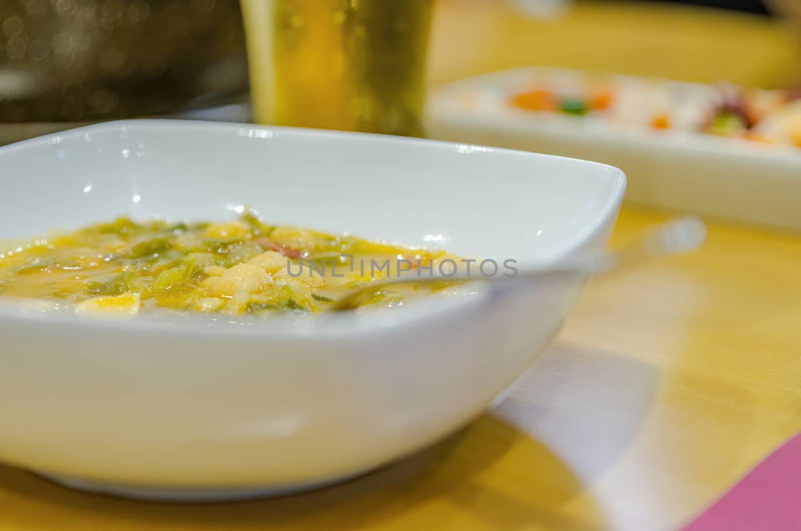 White plate of bean stew. Home-cooked food. Accompanied by cold beer. Restaurant menu of the day