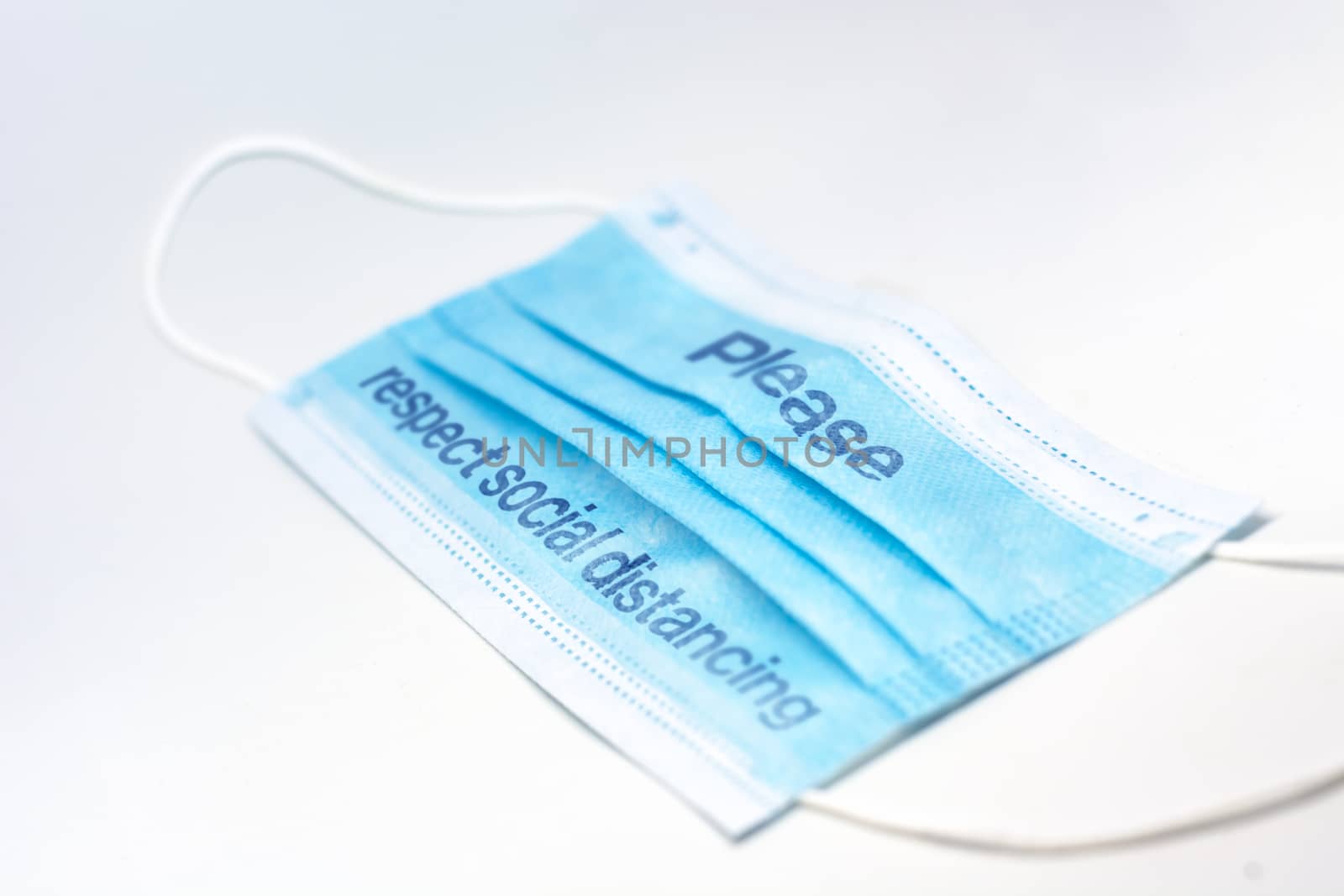 blue surgical mask with the indication to maintain social distancing and not to stay so close. Covid-19 pandemic and social distancing to prevent the spread of the virus