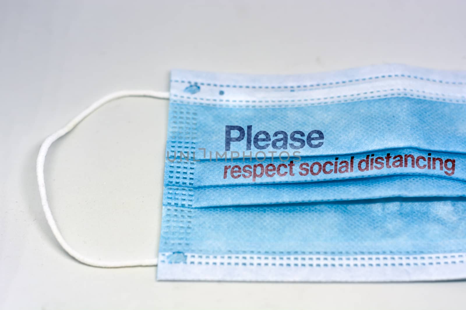 blue surgical mask with the indication to maintain social distancing and not to stay so close. Covid-19 pandemic and social distancing to prevent the spread of the virus
