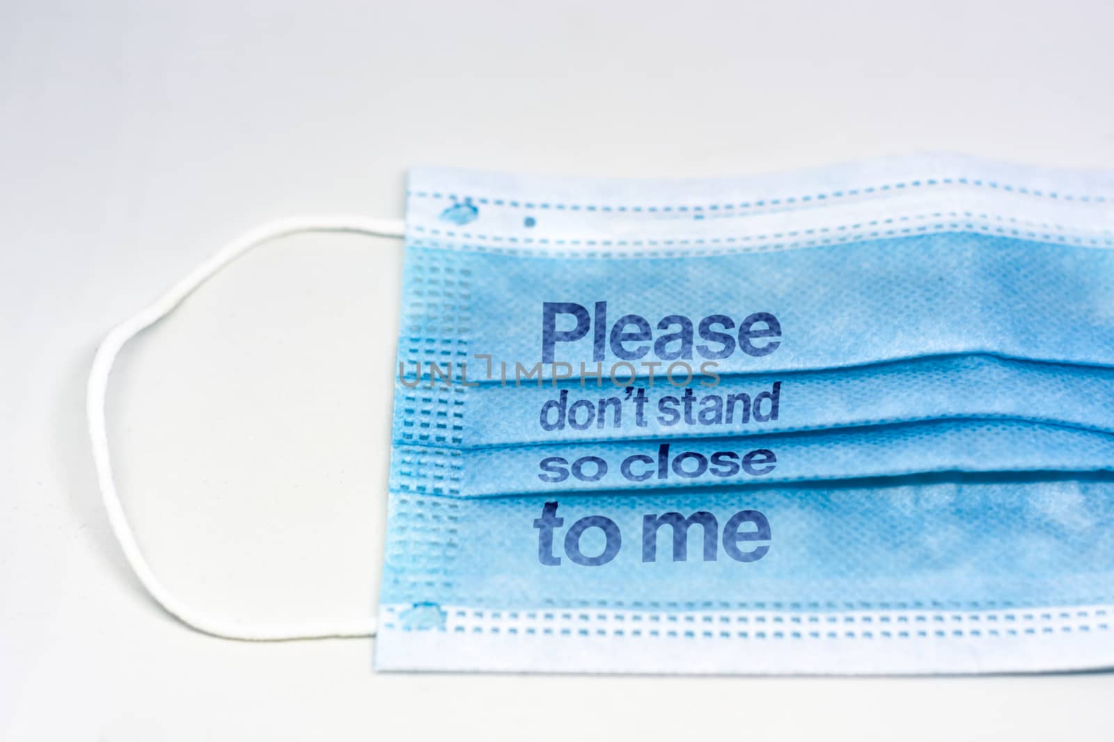 blue surgical mask with the indication to maintain social distancing and not to stay so close. Covid-19 pandemic and social distancing to prevent the spread of the virus