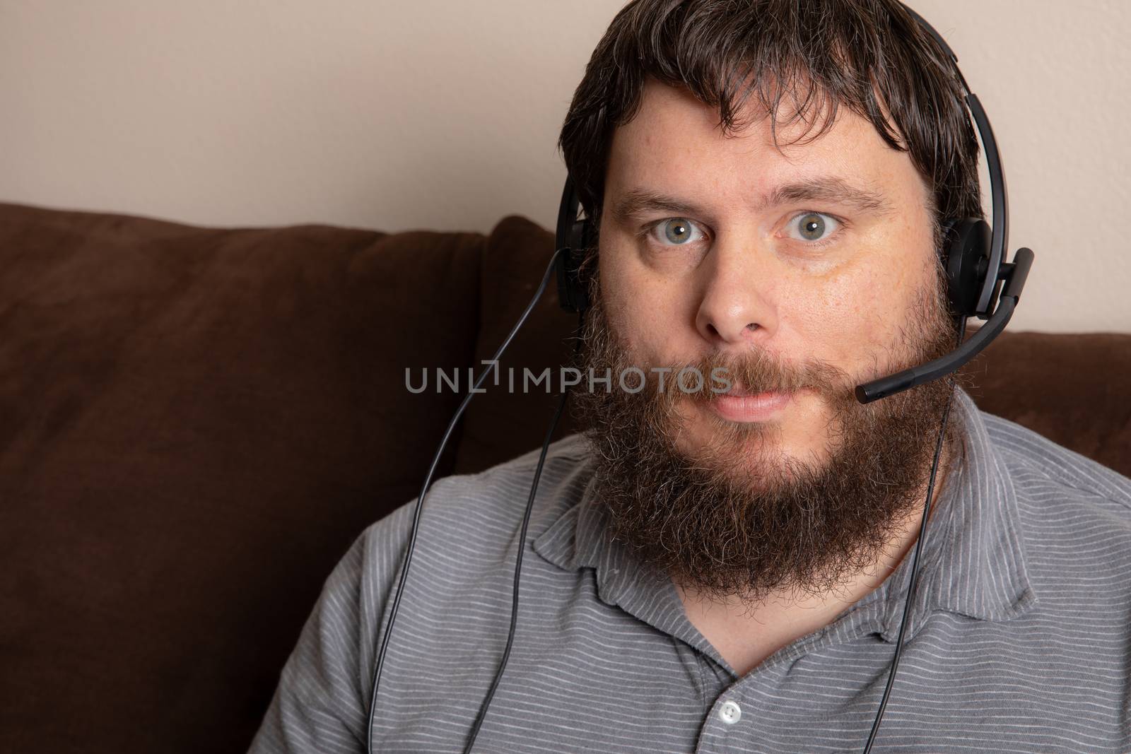 Man having a confrence wearing his headset while from home.