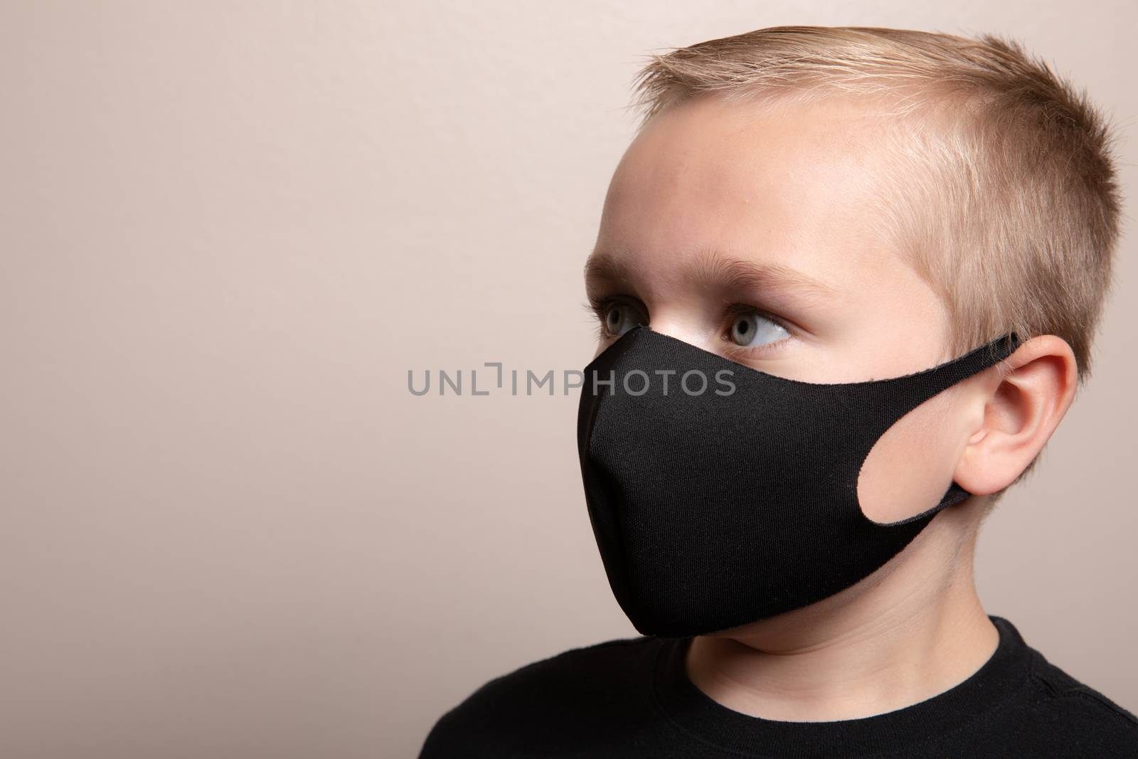 Young boy with a black face mask on trying to prevent the spread of germs