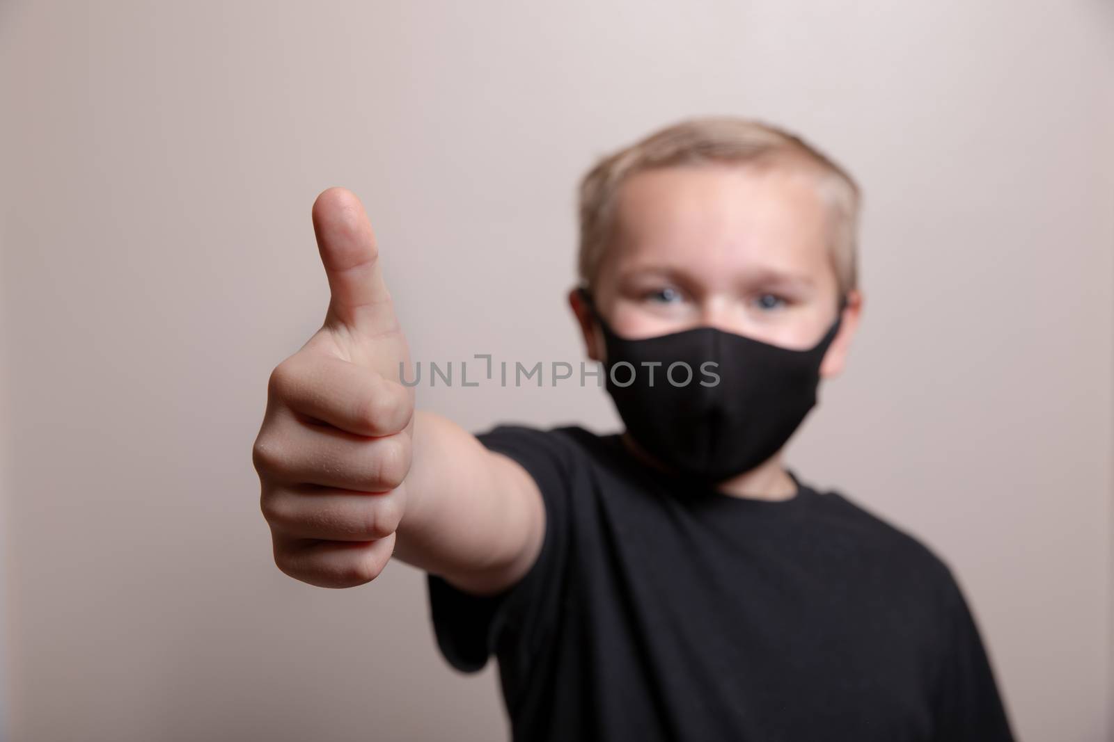 Young boy giving the positive thumbs up while wearing his face mask