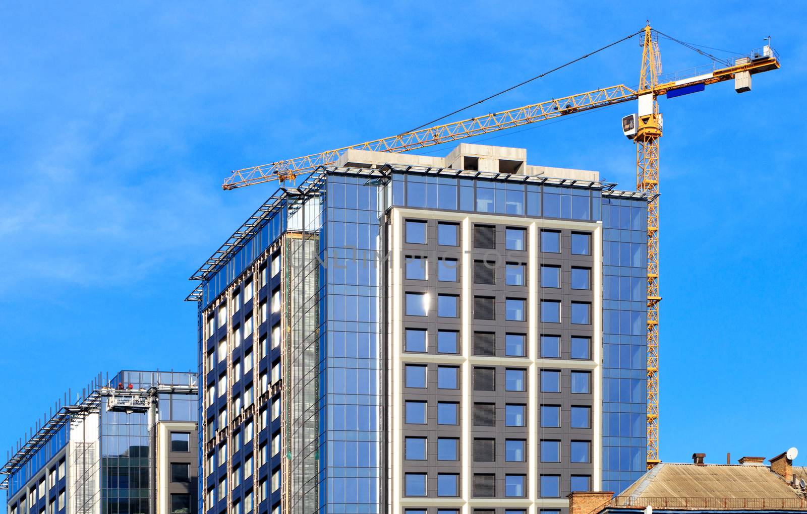 In the construction of modern residential concrete buildings with a glass facade, a tower crane is used, the old residential areas of the city are updated, image with copy space.