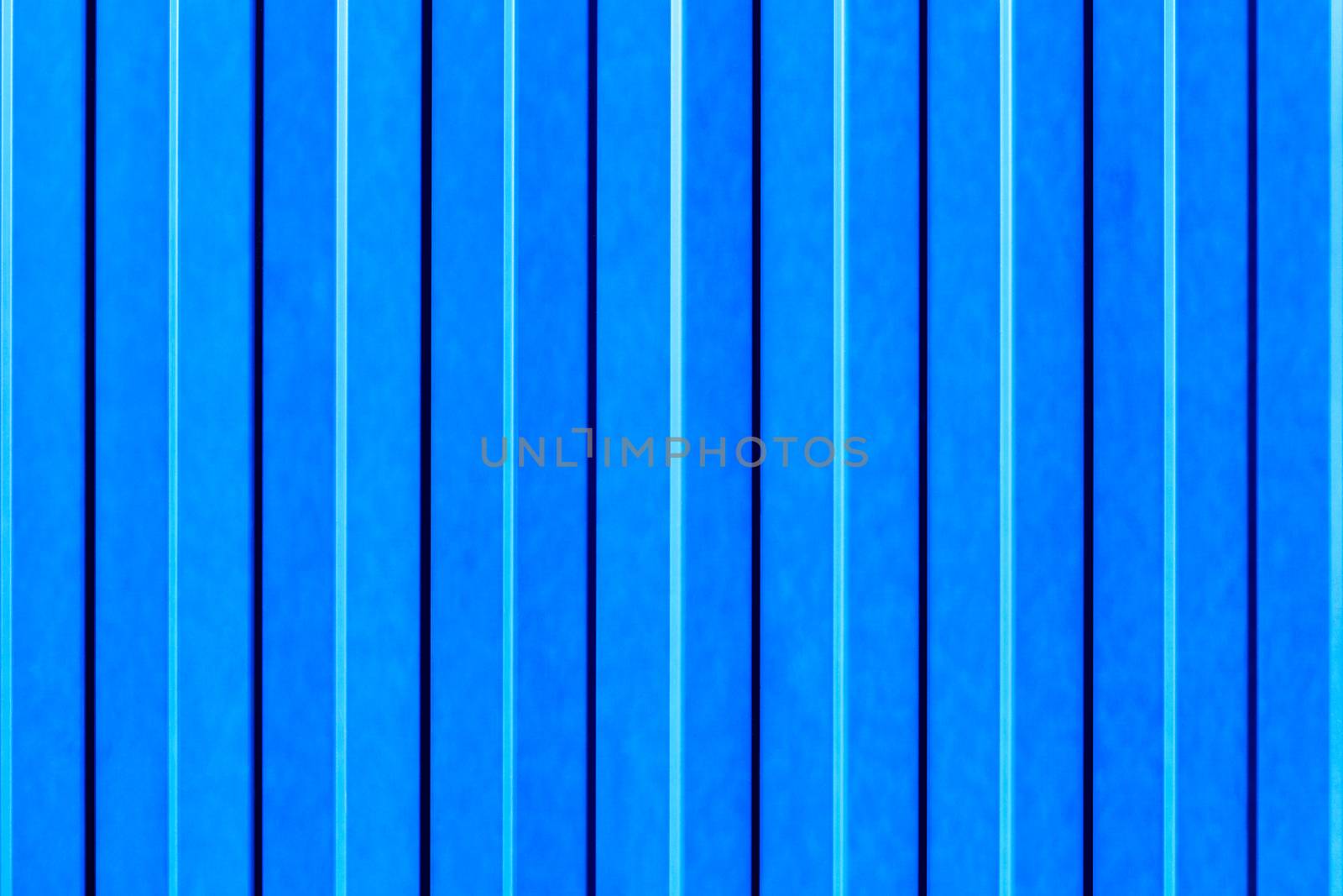 Light blue metallic fence made of corrugated steel sheet with vertical guides.