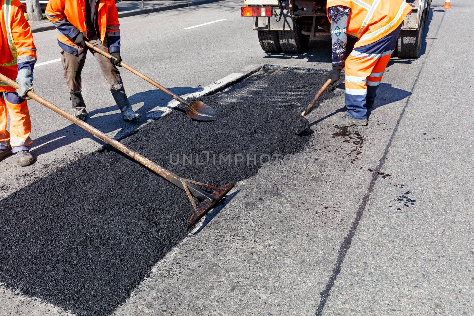 The workers' brigade clears a part of the asphalt with shovels in road construction by Sergii