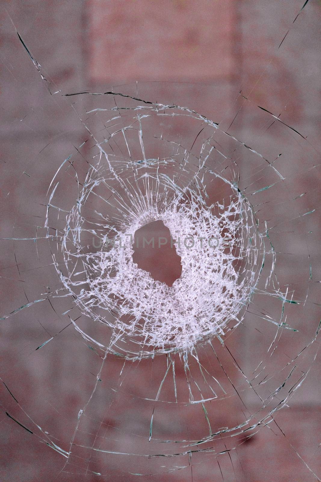 Bullet hole in the glass on a blood red background. by Sergii