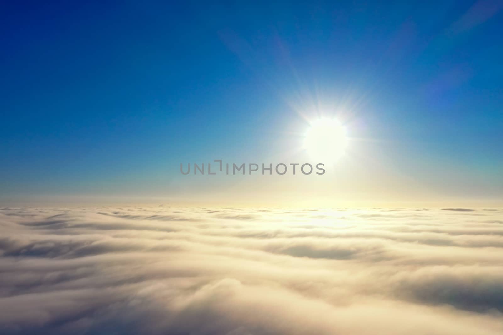 Bright sun in the blue sky over the horizon and a cover of dense gray clouds. by Sergii